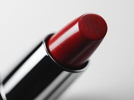 close up view of luxury lipstick bullet in classic red reveals embossed logo tip. vibrant color contrasts beautifully minimalist white backdrop highlighting its elegance photo