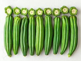 Fresh okra pods are neatly arranged in fan shape highlighting their smooth green surfaces and unique texture. background is plain white enhancing freshness of pods photo