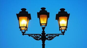 A street lamp stands against a blue sky, with lights photo