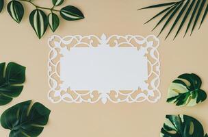 Trendy summer composition made with green tropical leaves and paper card note on sand color background. Minimal concept. Exotic flat lay. Creative copy space. photo