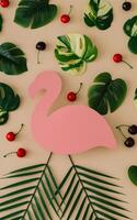 Summer pattern made of green tropical leaves and red cherry fruit with pink flamingo paper card note on sand color background. Minimal summer concept. Exotic flat lay. Creative copy space. photo