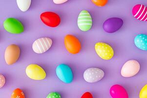 Trendy spring pattern made of colorful Easter eggs on purple background. Minimal Easter concept. Creative festive holiday layout. Easter aesthetic. Flat lay, top of view. photo