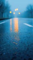 Wet asphalt road reflecting streetlights in a foggy evening scene, Atmospheric urban landscape with blurred background, Nighttime and weather concept photo
