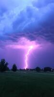 Dramatic Lightning Strike Against Dark Cloudy Sky Capturing Intense Stormy Atmosphere with Vibrant Purple and Blue Hues in Scenic Landscape Setting During Evening Thunderstorm photo
