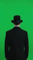 Magician Facing Green Screen Background in Black Suit and Hat for Illusion Concepts in Modern Photography and Digital Effects photo