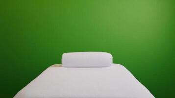 Spa Massage Table with Rolled Towel Against Bright Green Screen Background for Relaxation and Wellness Themes photo