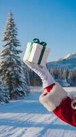 Papa Noel mano participación regalo caja en contra azul cielo, sereno invierno ajuste vertical móvil fondo de pantalla foto
