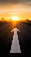 Asphalt road with white arrow pointing toward glowing sunset horizon Vertical Mobile Wallpaper photo