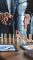 Wooden blocks toppling with hands in business attire, emphasizing strategic decision-making. Vertical Mobile Wallpaper photo