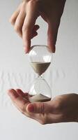 Hourglass Hand holds sand filled hourglass, emphasizing times fleeting nature Vertical Mobile Wallpaper photo