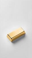 On a blank white surface, a single gold ingot is placed with a faint shadow underneath, providing space for text. photo