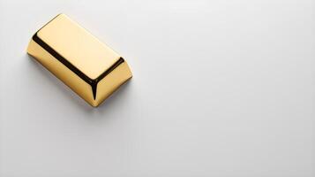 Resting on a smooth white surface, a single gold ingot is accompanied by a gentle shadow below, leaving space for text. photo