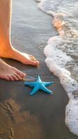Bare feet on wet sand, starfish beside ocean waves, golden sunlight glow Vertical Mobile Wallpaper photo