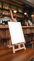 Wooden easel with blank canvas on a table in a rustic cafe Vertical Mobile Wallpaper photo