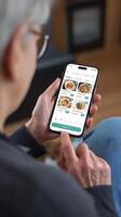Senior browses food delivery app, focusing on vegan and diverse dining options Vertical Mobile Wallpaper photo