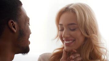 A biracial couple enjoys a tender moment together at home, exchanging smiles and affection. Their connection reflects love and warmth, showcasing their strong bond as spouses. video