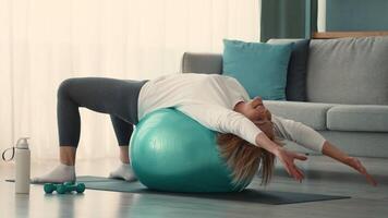 A senior woman engages in her daily fitness routine at home, using a stability ball for stretching. She demonstrates dedication to her health and well-being with mindful exercise. video