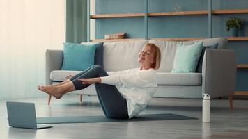 A senior woman performs an exercise routine at her home. She is focused and smiling while engaging in fitness activities, showing determination and enthusiasm for her health. video