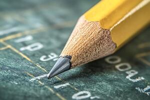 Short graphite pencil pointing numbers on green chart photo