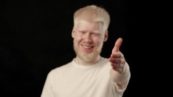 This young man with white hair and pale skin shares a cheerful moment. His bright expression contrasts with the dark background, creating a striking visual. He embodies a sense of joy and confidence. video