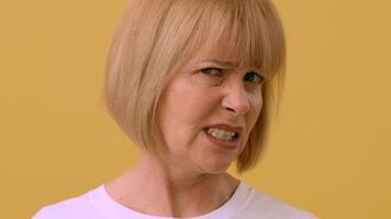 A woman expresses confusion while looking directly at the viewer, standing in front of a bright yellow backdrop that enhances her thoughtful demeanor. video