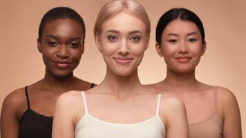 Three women of different backgrounds pose in natural light, showcasing their smiles. Their confident expressions highlight beauty, unity, and diversity in a warm setting. video