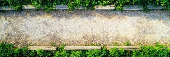 Aerial view of gravel pathway lined with wooden logs and green foliage in summer photo