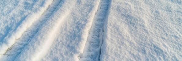 Snow-covered tire tracks creating patterns in fresh winter landscape photo
