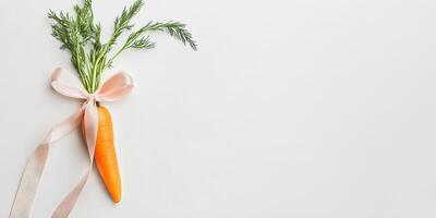 Fresh orange carrot with green leaves tied in a pink ribbon for decorative arrangements photo