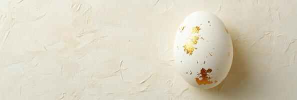 Elegant white egg with gold leaf on textured background for luxurious decor and art design photo