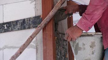 Construction workers man using containers to pour mixed cement into building column molds for reinforcement. A male professional is working at a building construction site.mov video