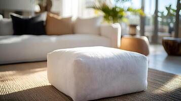 Modern white fabric ottoman showcases clean lines and linen texture against blurred indoor setting, embodying minimalist design with sophisticated lighting. design photo