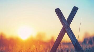 Rustic Wooden Cross Silhouette at Sunset in a Field of Grass photo