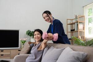 Caregiver assisting elderly client with physical exercise using dumbbells in a supportive home environment photo