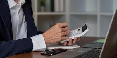 Senior financial consultant using calculator and reviewing notes in a stylish office workspace photo