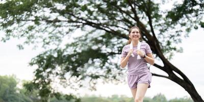 Cheerful woman jogging in the park enjoying fitness and fresh air during morning exercise photo