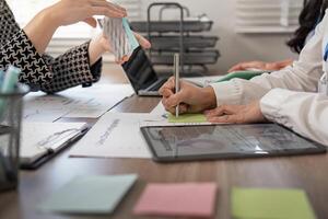 Professionals collaborating on data analysis and notetaking during an interactive business meeting at a modern office photo
