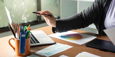 Graphic designer using a stylus at her desk while exploring color palettes and digital tools photo