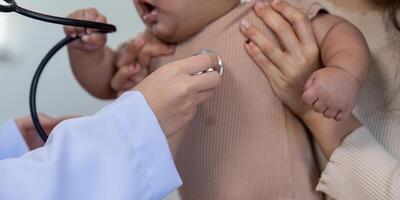 Doctor using stethoscope on baby during a pediatric checkup with parent support photo