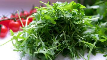 Fresh arugula leaves in bowl on stone background, top view video