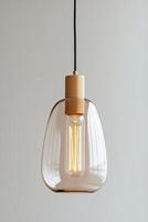 Sleek pendant light with a warm amber glow illuminates a cozy room, hanging from a ceiling. The minimalist design complements a softly colored wall while adding a touch of elegance photo