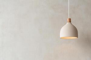 Warm amber glow of a Nordic-style pendant light enhances the cozy atmosphere of a modern interior, complementing a muted gray wall with ample negative space for design versatility photo