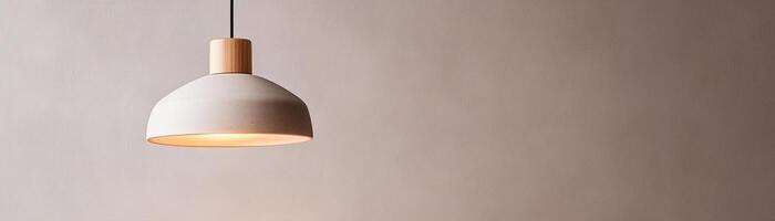 A sleek pendant light with a warm amber glow hangs from the ceiling against a muted gray wall. The minimalistic design enhances the cozy atmosphere while leaving space for text photo