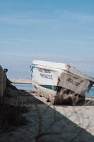 The weathered fishing boat sits docked at the port, with peeling paint and rust, reflecting its years of use photo