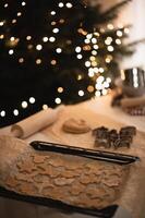 Gingerbread dough is spread out on the table, and cookie cutters are ready to make festive shapes. photo