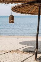 Charming straw beach umbrellas on a serene Greek beach with crystal-clear sea and a vibrant blue sky. photo