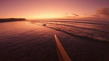 Surfer first-person view staying with a surfboard on beach in ocean. Crashing waves at bright sunset or sunrise video