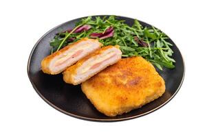 Chicken cordon bleu cutlet with cheese and ham on plate with salad isolated on white backgroun photo