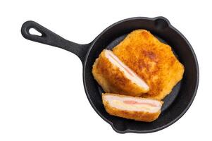 Fried cordon bleu cutlet with cheese and ham in pan isolated on white background. top view photo