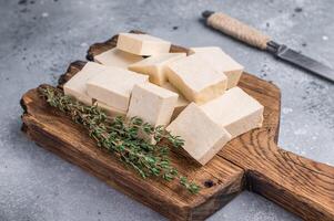 Organic Diced soy tofu cheese on wooden board. grey background. top view photo